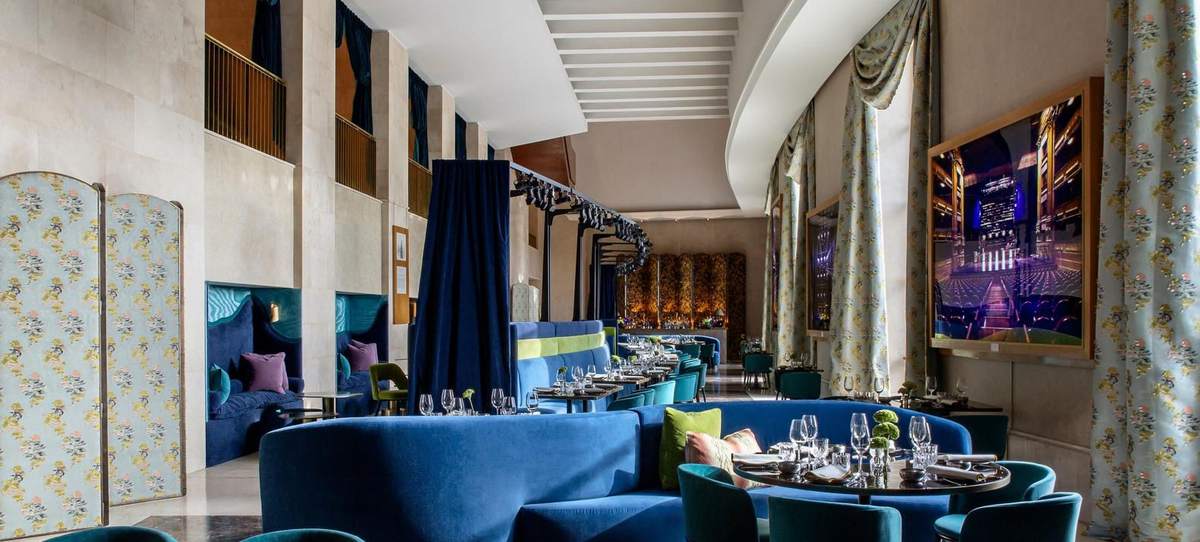 Sala de Papagena montada para un grupo, con sofás azules y ventanales